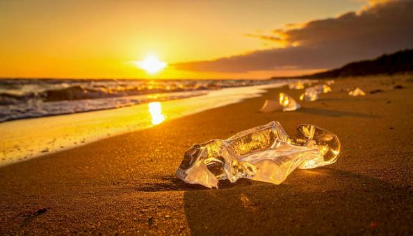 砂浜に打ち上げららえた流氷　夕日の写真