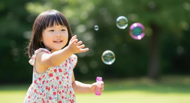 シャボン玉で遊ぶ笑顔の女の子の写真