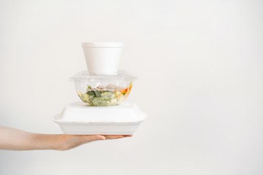 積まれたフードパックを差し出す手 配達,フードデリバリー,テイクアウトの写真素材