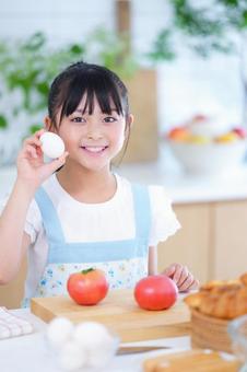 エプロン姿で卵を見せる可愛らしい少女 女の子,小学生,日本人の写真素材