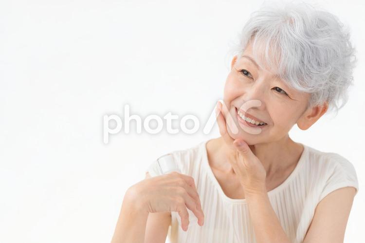 白バックでスキンケアをするシニアの女性 ビューティー,女性,シニアの写真素材