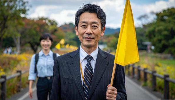 旗を持って旅行客を導く男性の旅行添乗員の写真