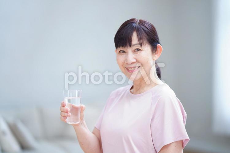 水を手に明るく微笑む中年女性 主婦,シニア,立ち姿の写真素材