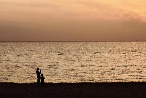 冬のマジックアワーの海岸の親子の影 海岸,冬,日没後の写真素材