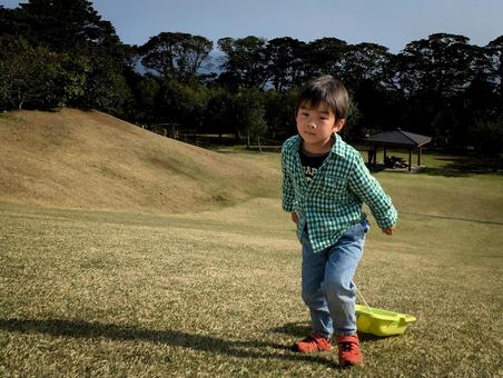 <素材>公園の芝生でそり遊びをする男の子 <素材>公園の芝生でそり遊びをする男の子の写真