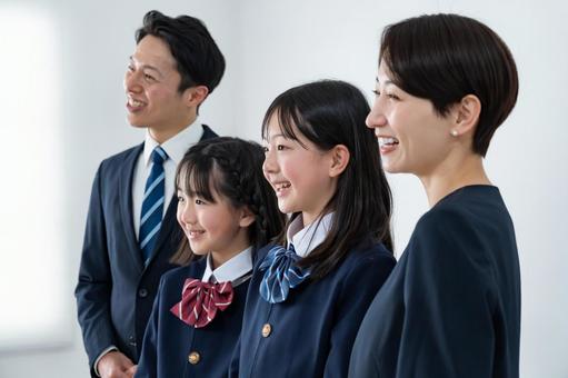 スーツを着た男女と制服を着た女の子二人 スーツを着た男女と制服を着た女の子二人 入学式,父母,母親の写真素材