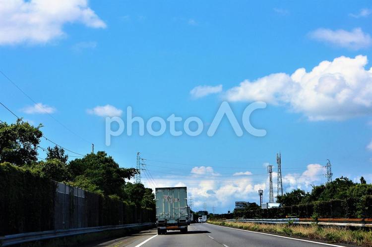 スッキリした青い空に浮かぶ雲と、たくさんの鉄塔が並ぶ高速道路 青空,道路,空の写真素材
