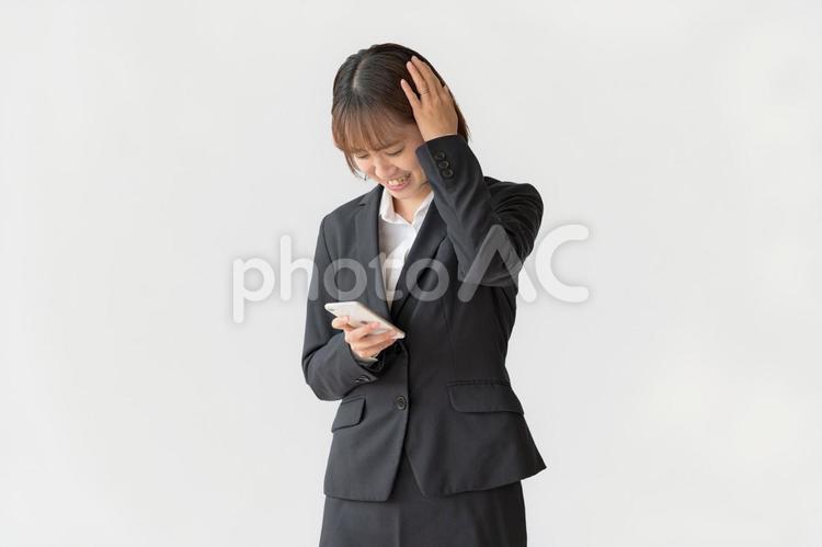 スマホと悩む女性 頭を抱える,困惑,悩むの写真素材