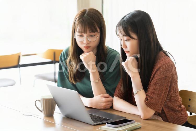 パソコンを使いながら考える2人の女性 女性,考える,悩むの写真素材