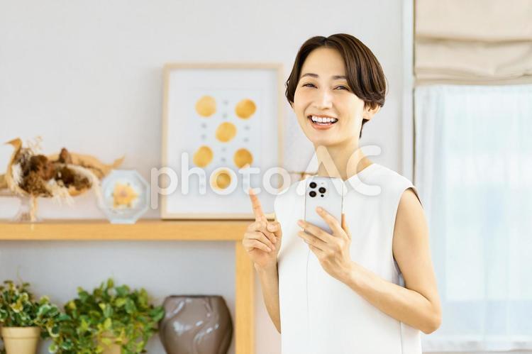 スマホを持つ笑顔の女性　部屋　夏 スマホ,女性,主婦の写真素材