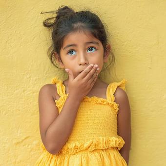黄色の背景で秘密をささやくような子供 黄色の背景で秘密をささやくような子供の写真