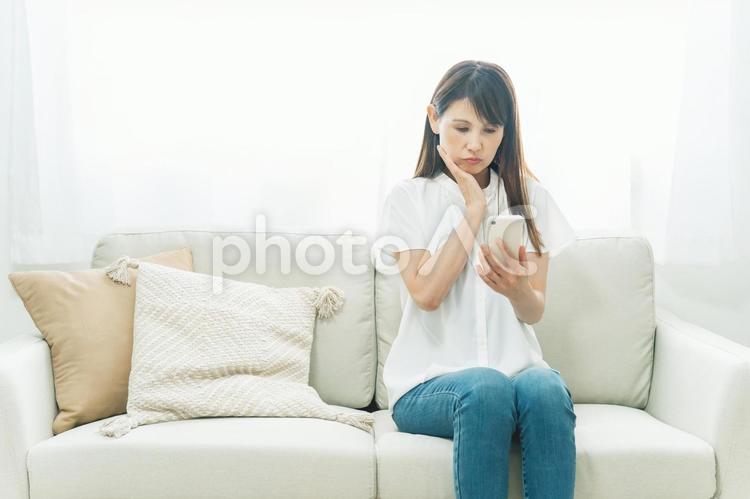 ソファに座るミドル世代の女性（困る） スマホ,アプリ,スマートフォンの写真素材