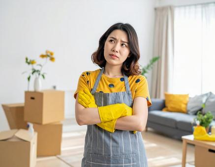 悩むエプロン姿の若い日本人女性の写真
