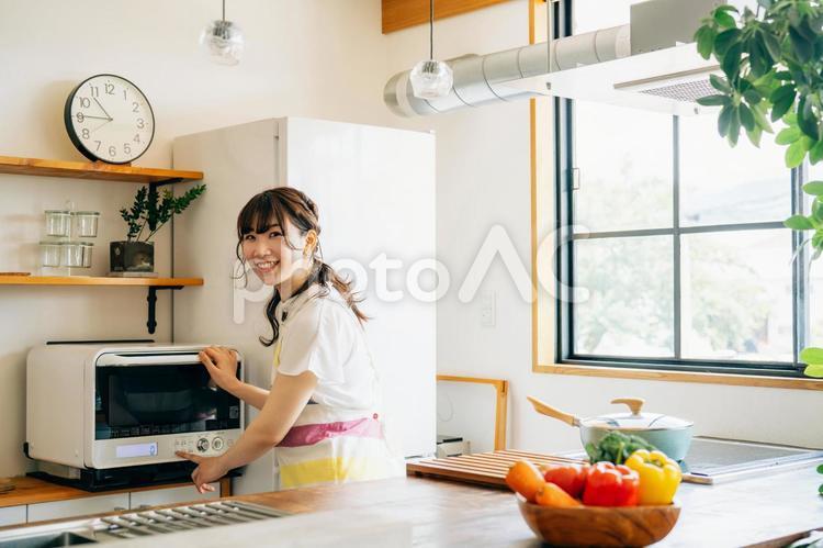 電子レンジを使う女性（笑顔） レンジ,電子レンジ,オーブンレンジの写真素材