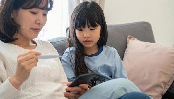 発熱した子供を心配して病院を検索する母 発熱した子供を心配して病院を検索する母の写真