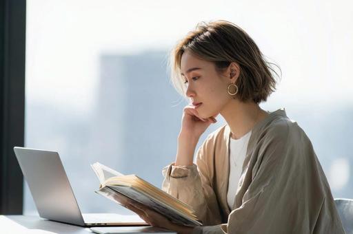 デスクで本を読むビジネス女性 デスクで本を読むビジネス女性の写真