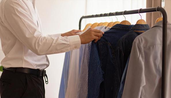 ハンガーにかかる私服を取るビジネスマン ハンガーにかかる私服を取るビジネスマンの写真