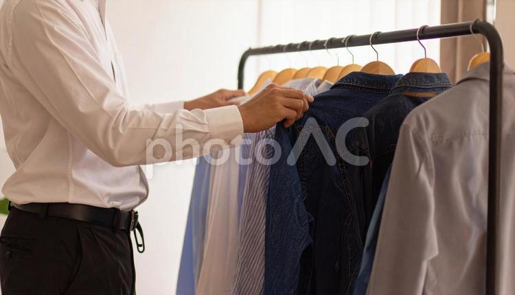 ハンガーにかかる私服を取るビジネスマン カジュアル,プライベート,ハンガーの写真素材