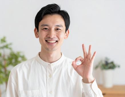 笑顔でOKサインをする白シャツ姿の男性 笑顔でOKサインをする白シャツ姿の男性の写真