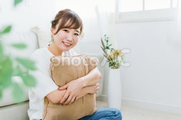 家でクッションを持つ笑顔のアジア人女性 女性,笑顔,笑うの写真素材