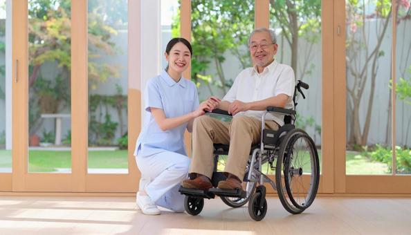 車椅子に乗った高齢男性と女性介護士 車椅子に乗った高齢男性と女性介護士の写真