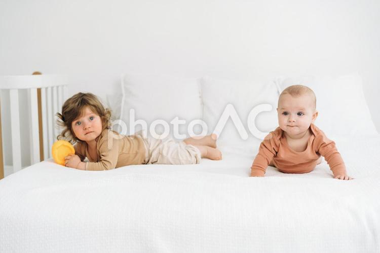 ベッドの上でうつ伏せになる子供たち 赤ちゃん,かわいい,ベッドの写真素材