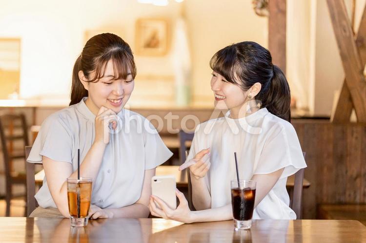 カフェでスマホを見ながら話すアジア人女性 スマホ,sns,アプリの写真素材