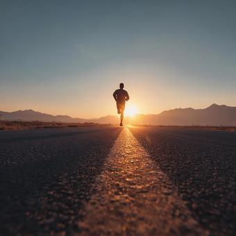 遠くまで続く道と、影になったランナー 遠くまで続く道と、影になったランナーの写真