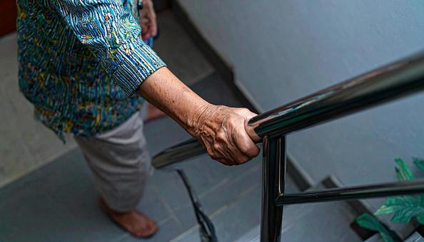 手すりにつかまって階段を上るシニア女性 手すりにつかまって階段を上るシニア女性の写真