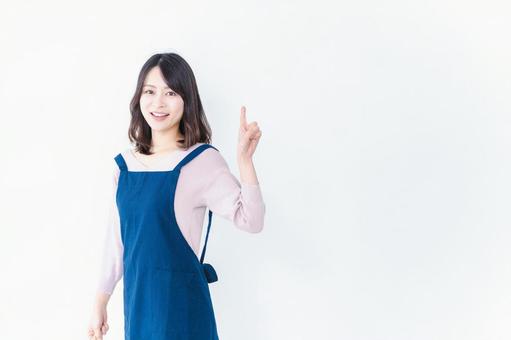 エプロンを着ておすすめを示す若い女性 エプロンを着ておすすめを示す若い女性の写真
