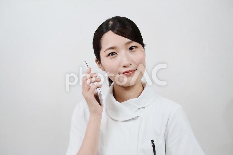 スマートフォンを操作する白衣の女性 予約,問い合わせ,病院の写真素材