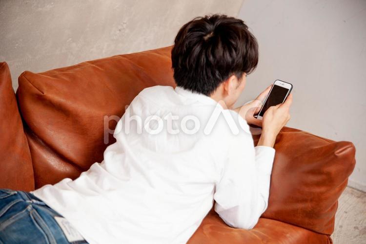 部屋でスマホをみる男性 スマホ,ゲーム,課金の写真素材
