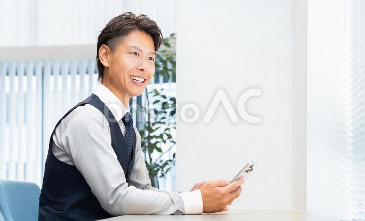 スマホを使う笑顔の男性ビジネスマン 男性,スマホ,スマートフォンの写真素材