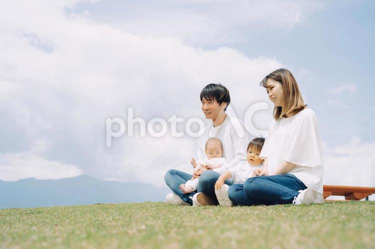 空と芝生に座る家族・ファミリー（4人） 家族,親子,赤ちゃんの写真素材