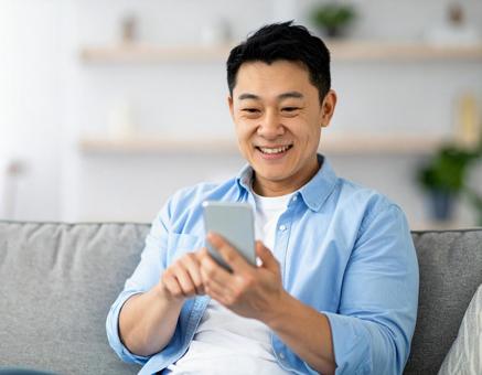 自宅でスマホを操作する男性c 自宅でスマホを操作する男性cの写真