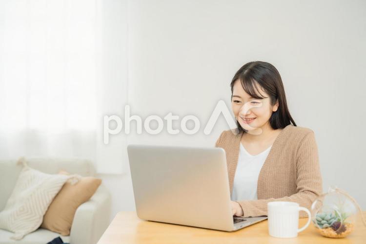 家でノートパソコンを使う女性（笑顔） パソコン,ノートパソコン,テレワークの写真素材