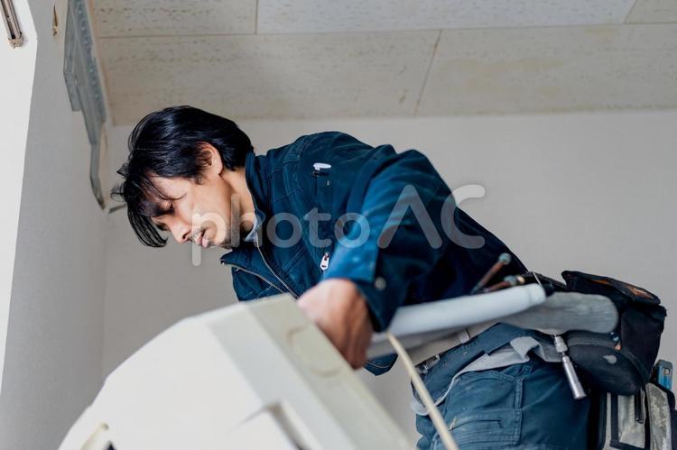 古いエアコンを下に置く電気工事作業員 ビジネス,ビジネスマン,男の写真素材