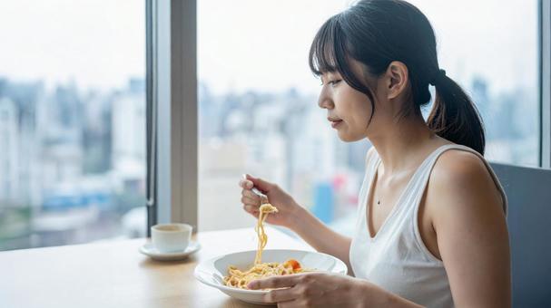 カフェでパスタを食べる女性の写真