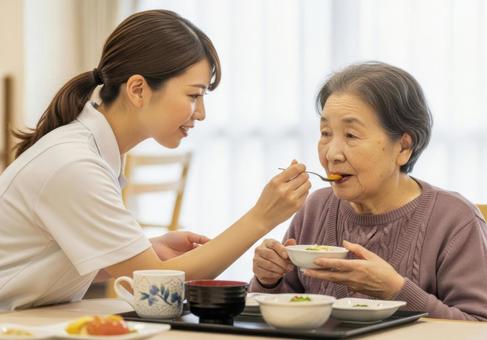 女性介護士が高齢女性に食事介助する場面 女性介護士が高齢女性に食事介助する場面の写真