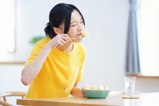 フォークに刺したフルーツを食べる笑顔の女性 女性,リンゴ,食べるの写真素材