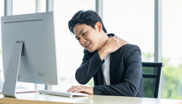 デスクワークで肩こりに悩むビジネスマン デスクワークで肩こりに悩むビジネスマンの写真