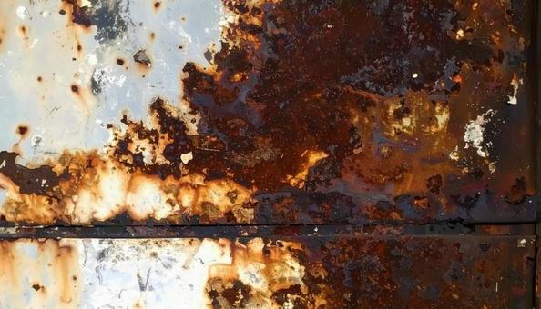 赤くサビてボロボロに朽ちた金属板の写真