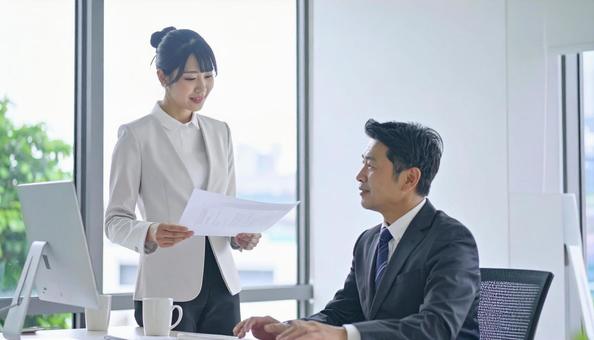 上司に報告する女性社員の写真