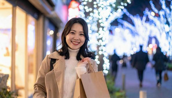 紙袋を手にする女性とイルミネーションの写真