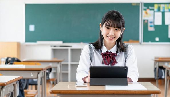 イヤホンをしてタブレットを見る女子学生 イヤホンをしてタブレットを見る女子学生の写真