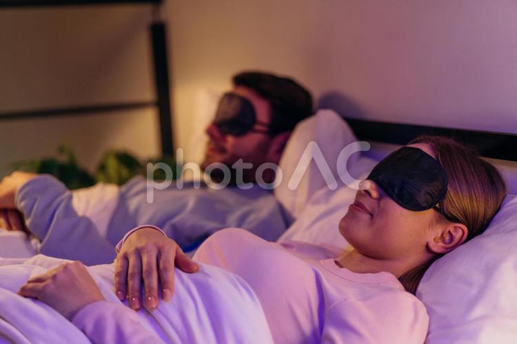 アイマスクをして寝ているカップル 女性,男性,ヒゲの写真素材