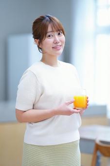 笑顔でオレンジジュースを持つ女性の写真