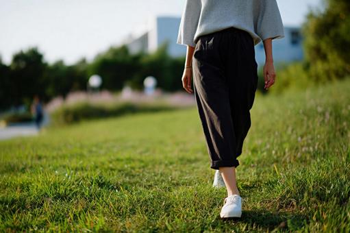 公園の芝生を散歩する女性 公園の芝生を散歩する女性の写真