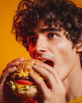視線が印象的なハンバーガーを食べる男性 視線が印象的なハンバーガーを食べる男性の写真