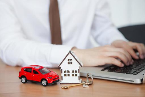 家と車の模型を前にしてタイピングする手元 保険業,事務職,接客業の写真素材